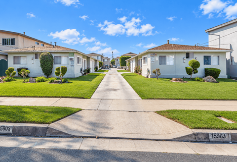 A residential street with houses on both sides and a clear blue sky above.