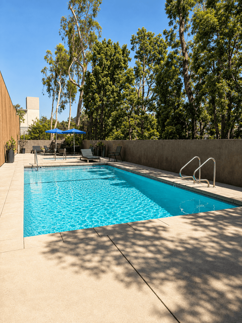 A pool with a blue umbrella and trees in the background.