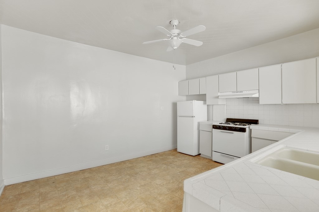 A white kitchen with a fan on the ceiling.