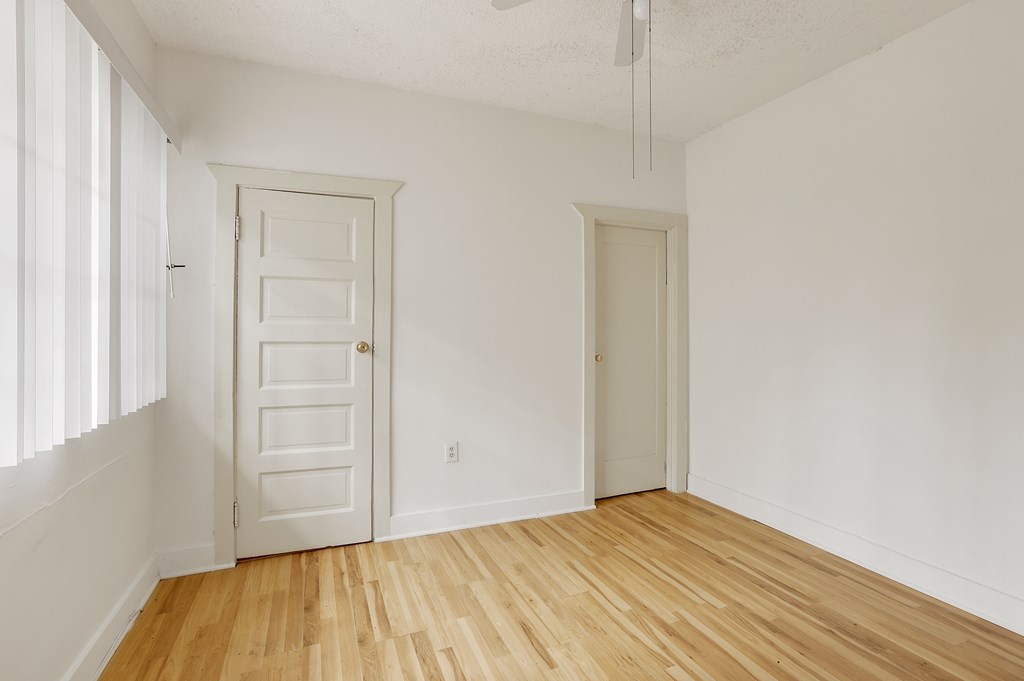 A room with a white door and a wooden floor.