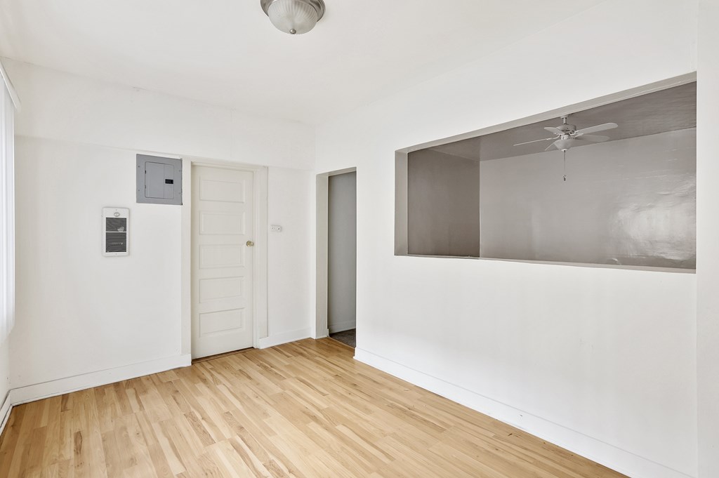 A room with a white ceiling, a white door, and a white wall with a small window.