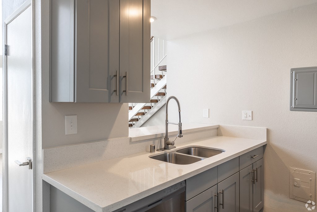 an empty kitchen with a sink and a staircase