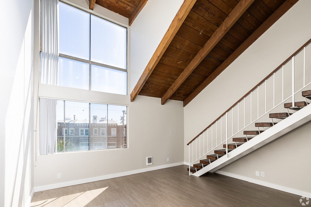 a living room with a staircase and large windows