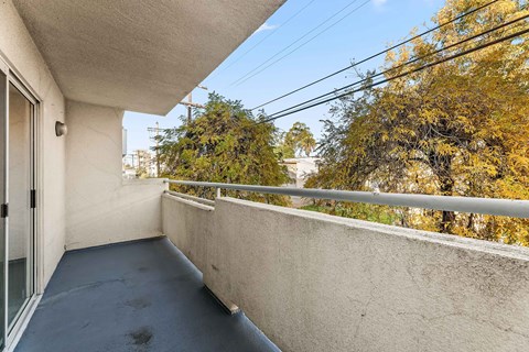 A balcony with a grey floor and a white wall.
