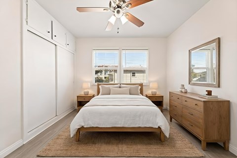 A bedroom with a bed, dresser, and window.