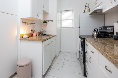 a kitchen with white cabinets and counters and a white refrigerator