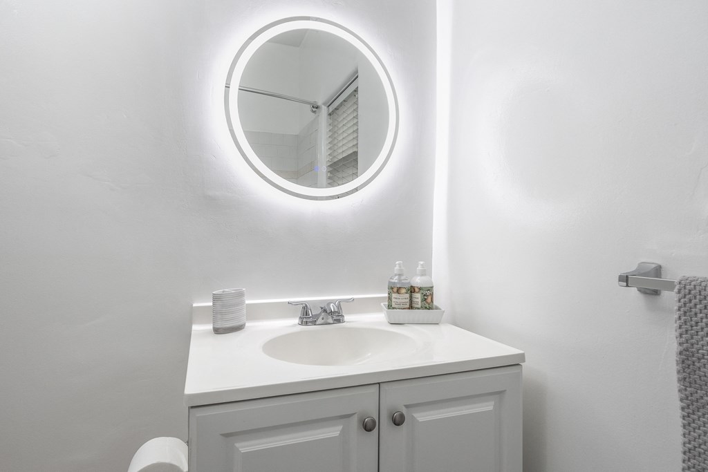 a white bathroom with a white sink and a white mirror