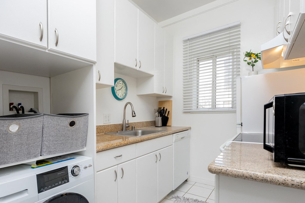a kitchen with white cabinets and a white washer and dryer