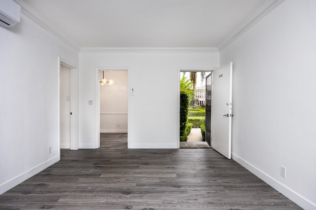a bedroom with white walls and a hardwood floor