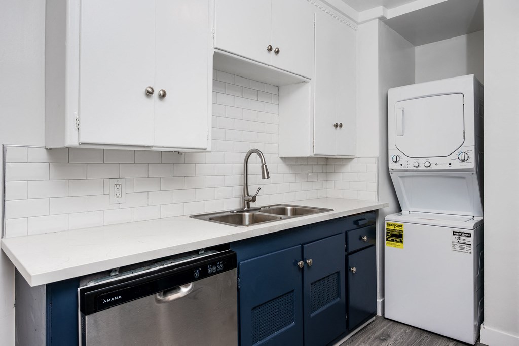 a kitchen with white cabinets and blue counters and a white washer and dryer