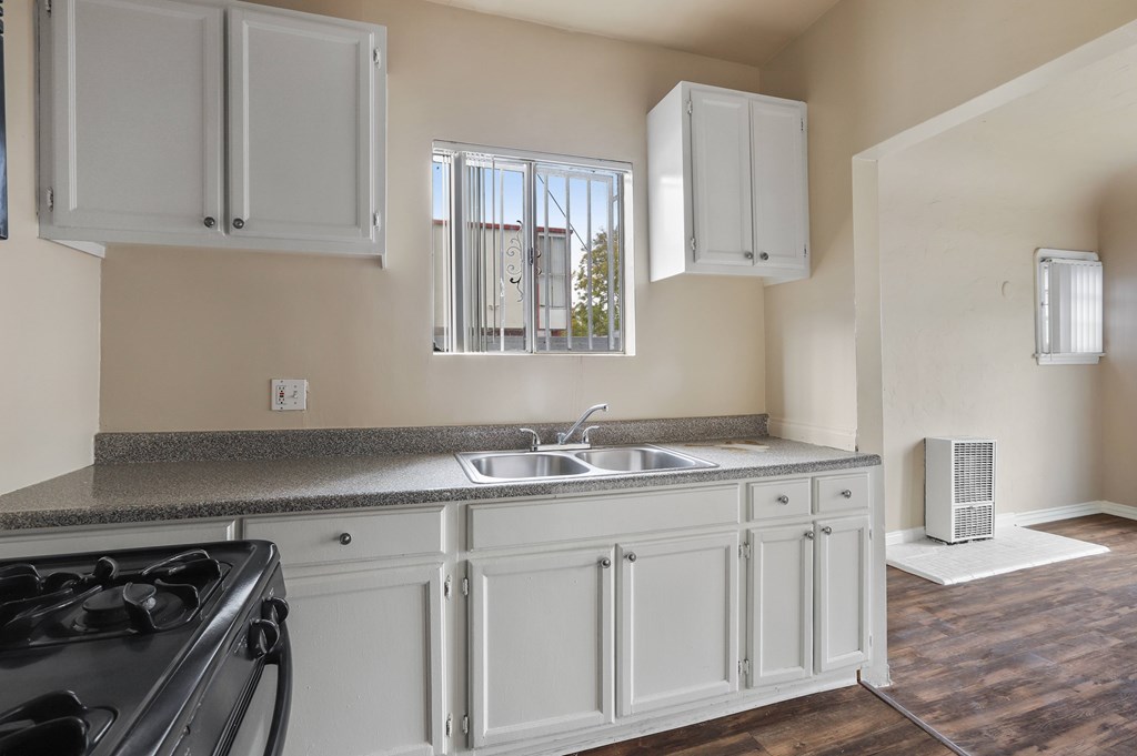 A kitchen with a black stove top oven and white cabinets.