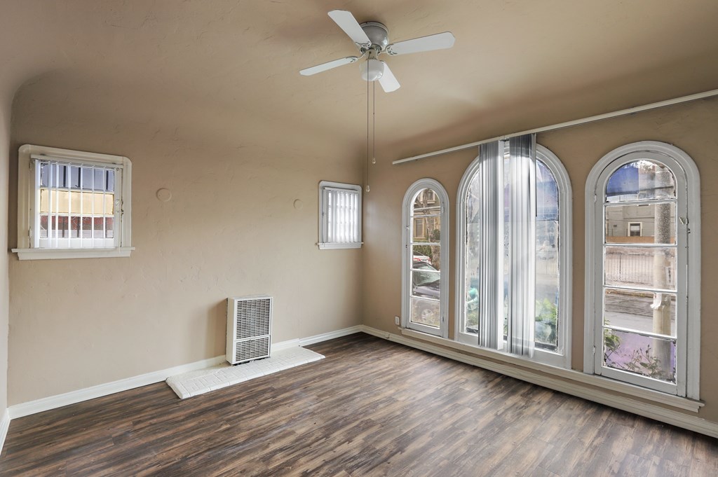 A room with a ceiling fan and a window with blinds.