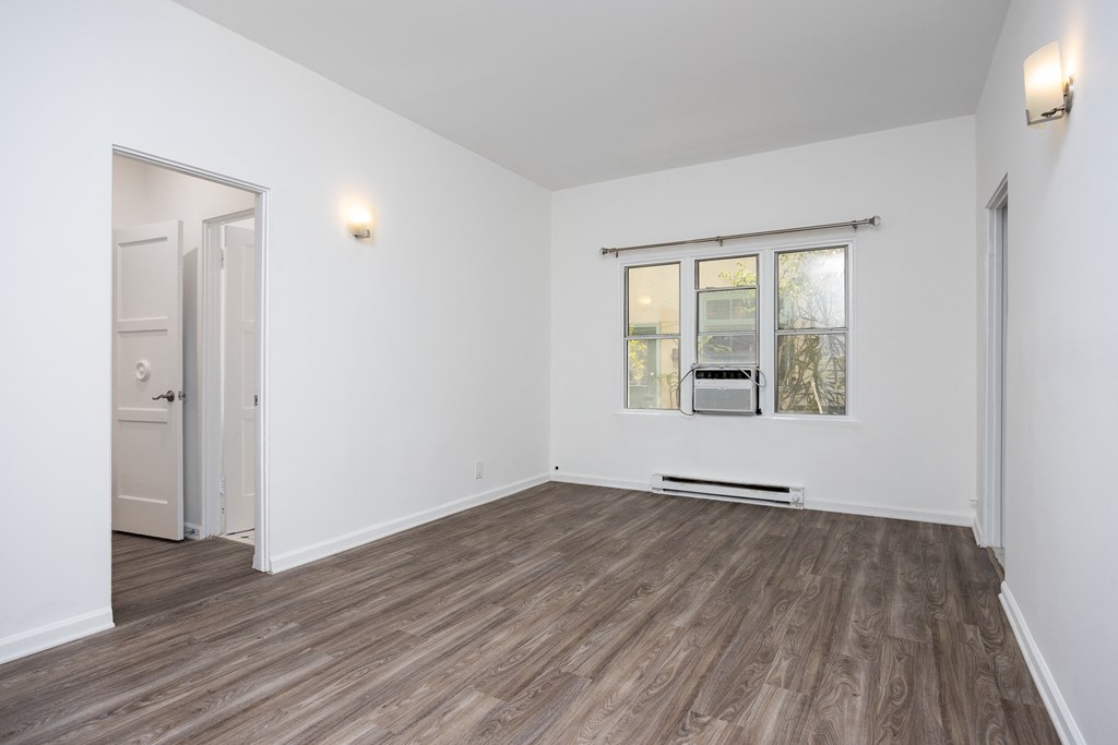 a bedroom with hardwood floors and white walls