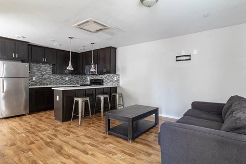 A kitchen with a refrigerator, stove, and island with a bar stool.