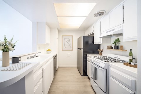 A modern kitchen with a black refrigerator and white cabinets.