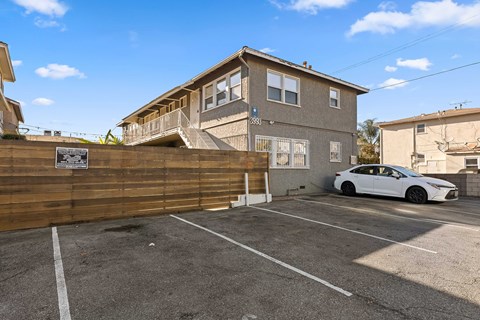 A white car is parked in a parking lot in front of a two-story building.