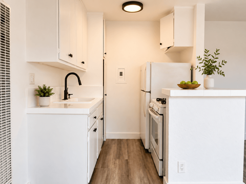 A white kitchen with a sink, stove, and refrigerator.