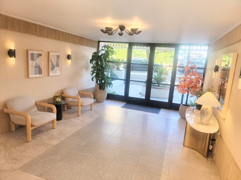 A well-lit waiting room with a table, chairs, and a plant.