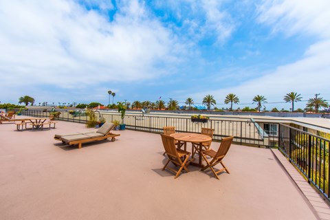 A patio with a table and chairs overlooking a pool.