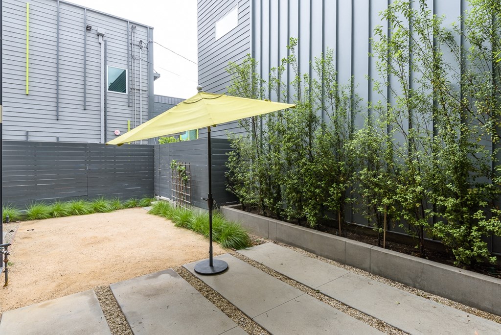 a small courtyard with a yellow umbrella in front of a building