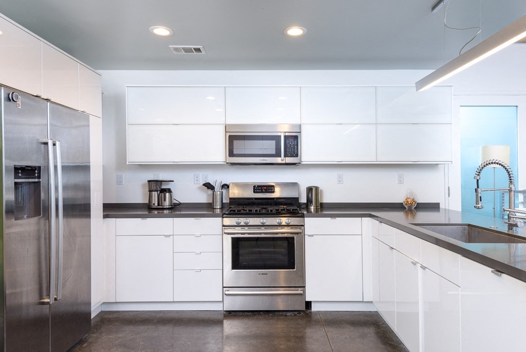 a white kitchen with stainless steel appliances and white cabinets