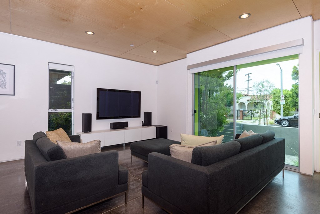 a living room with black couches and a television
