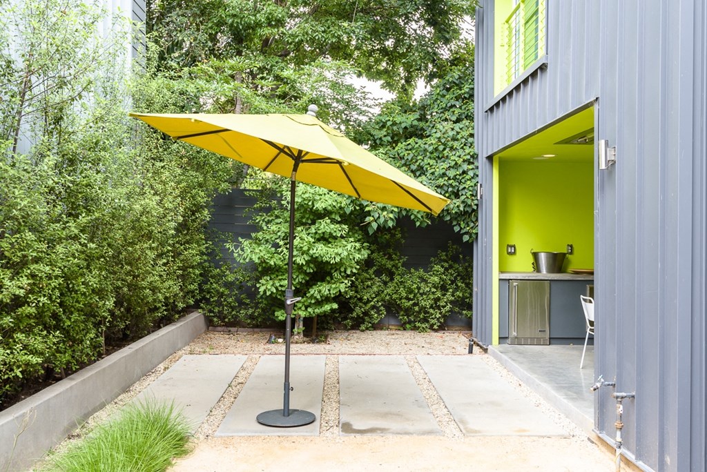 a patio with a yellow umbrella next to a blue building