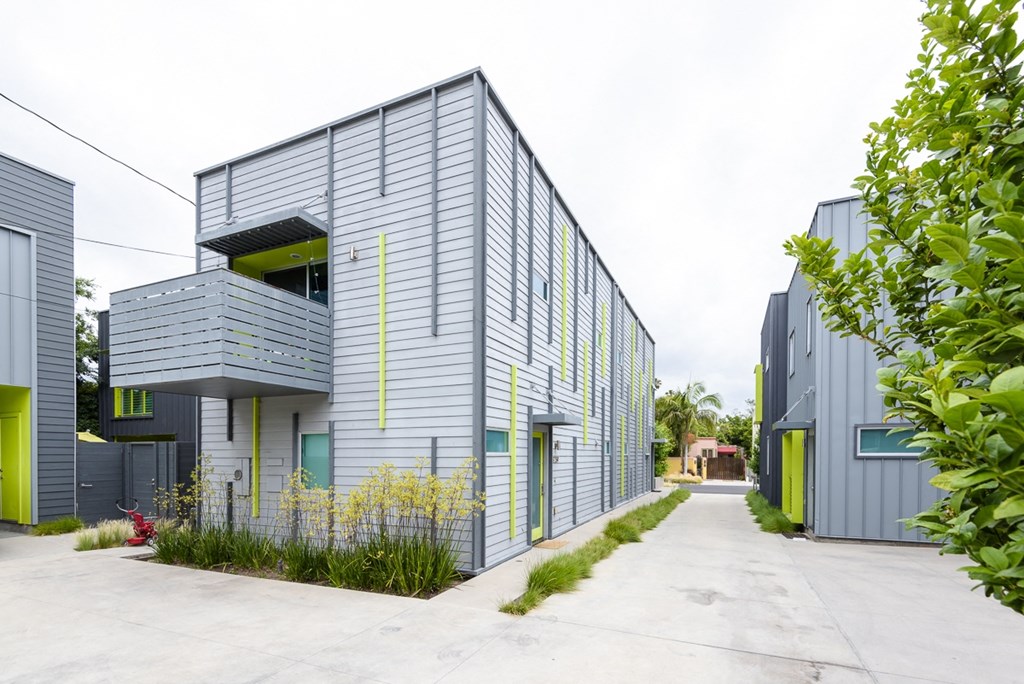 a row of houses with grey and green walls and a sidewalk