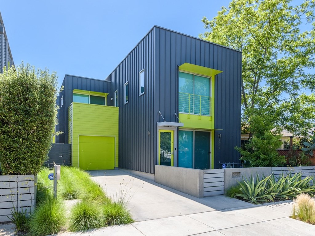 a black house with green doors and a sidewalk