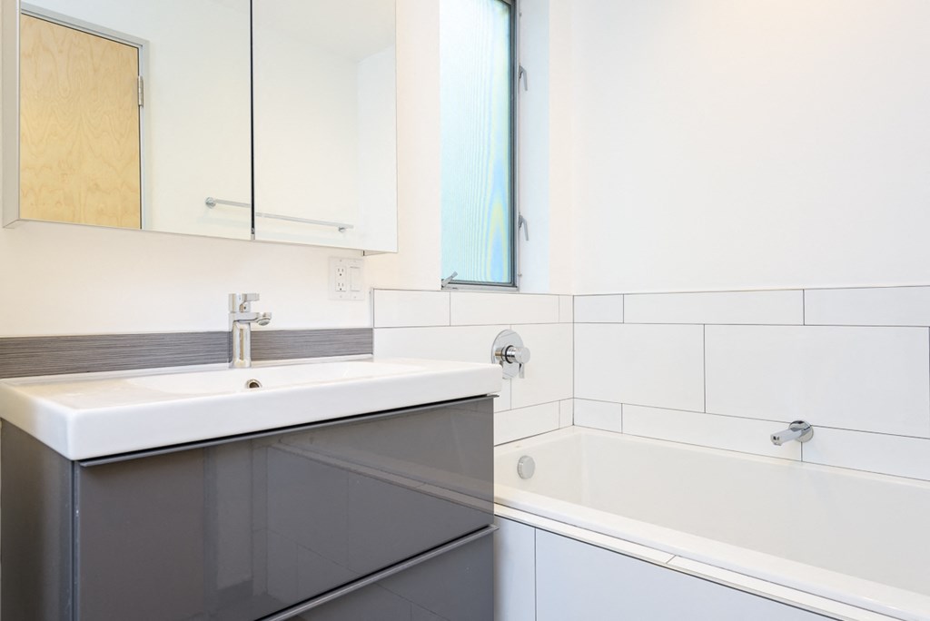 a white bathroom with a sink and a bath tub