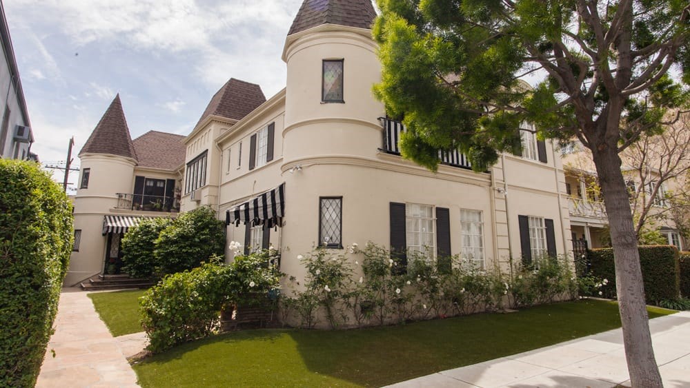 a large white house with a lawn and trees in front of it
