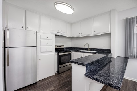 A kitchen with white cabinets and a black granite counter.