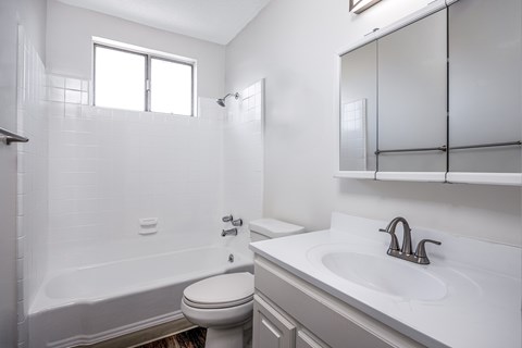 A white bathroom with a toilet, sink, and bathtub.