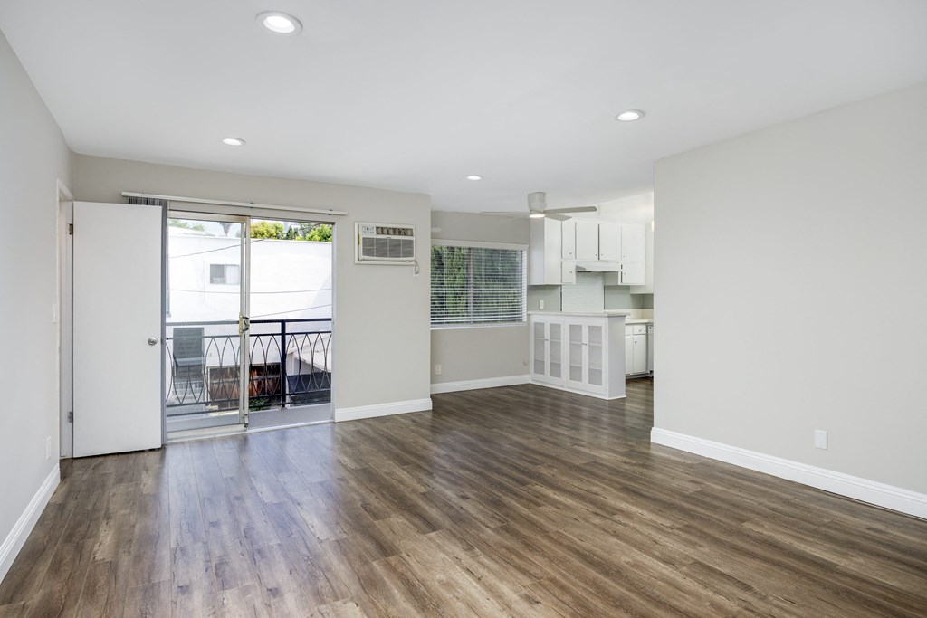 an empty living room with a balcony and a kitchen
