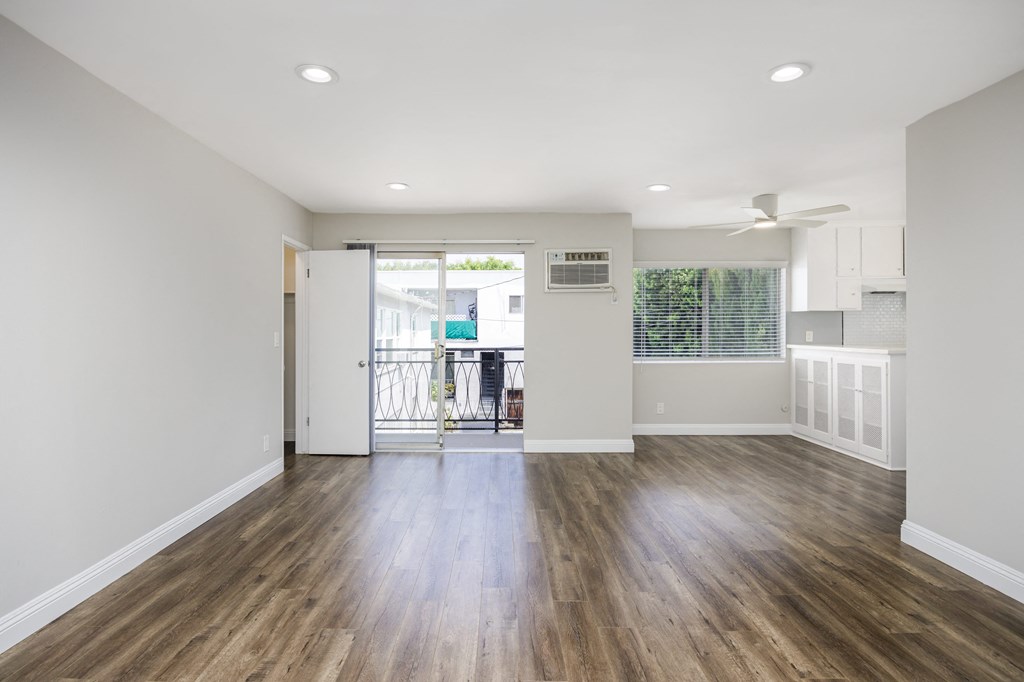 a living room with white walls and a door to a balcony