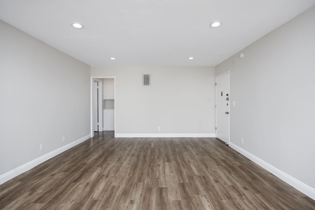 an empty living room with white walls and wood floors