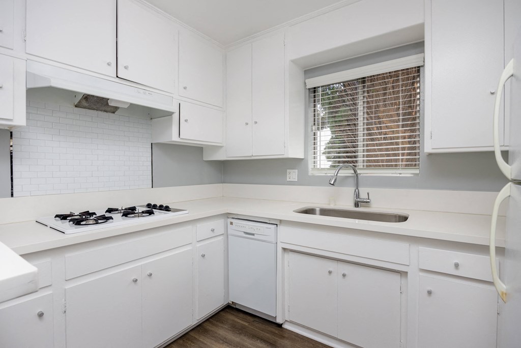 a kitchen with white cabinets and a sink and a window