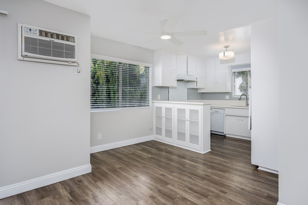 an open kitchen and living room with white walls and wood flooring