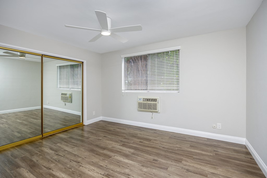 an empty room with a mirror and a ceiling fan