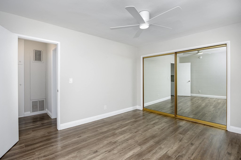 an empty living room with a mirror and a ceiling fan