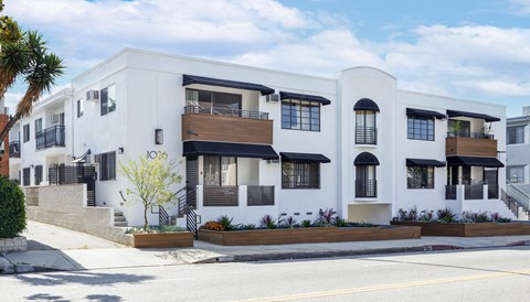 the exterior of a white building with black and white balconies and a street