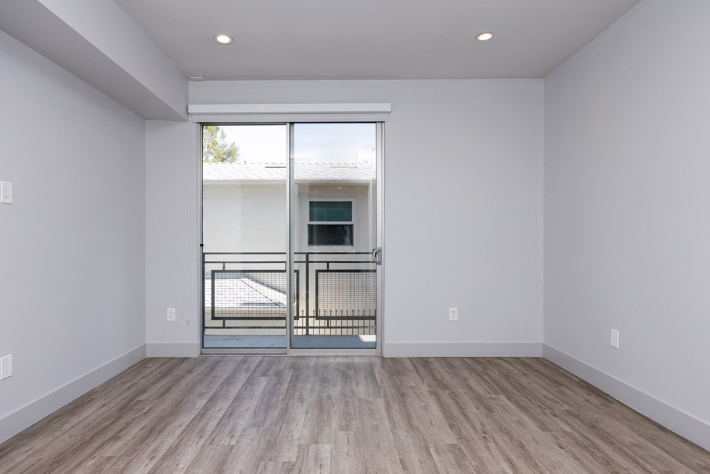 an empty living room with a sliding glass door to a balcony