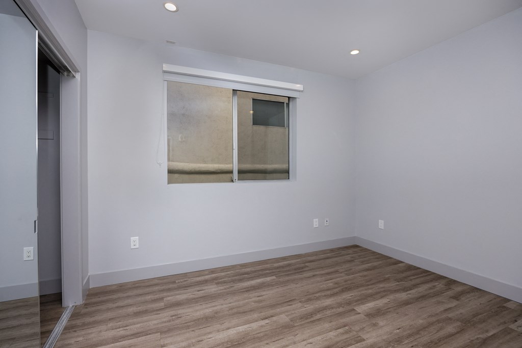 a room with white walls and a window and wood flooring