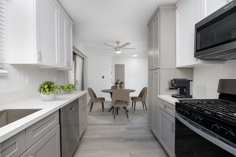 a kitchen and dining room with white cabinets and stainless steel appliances