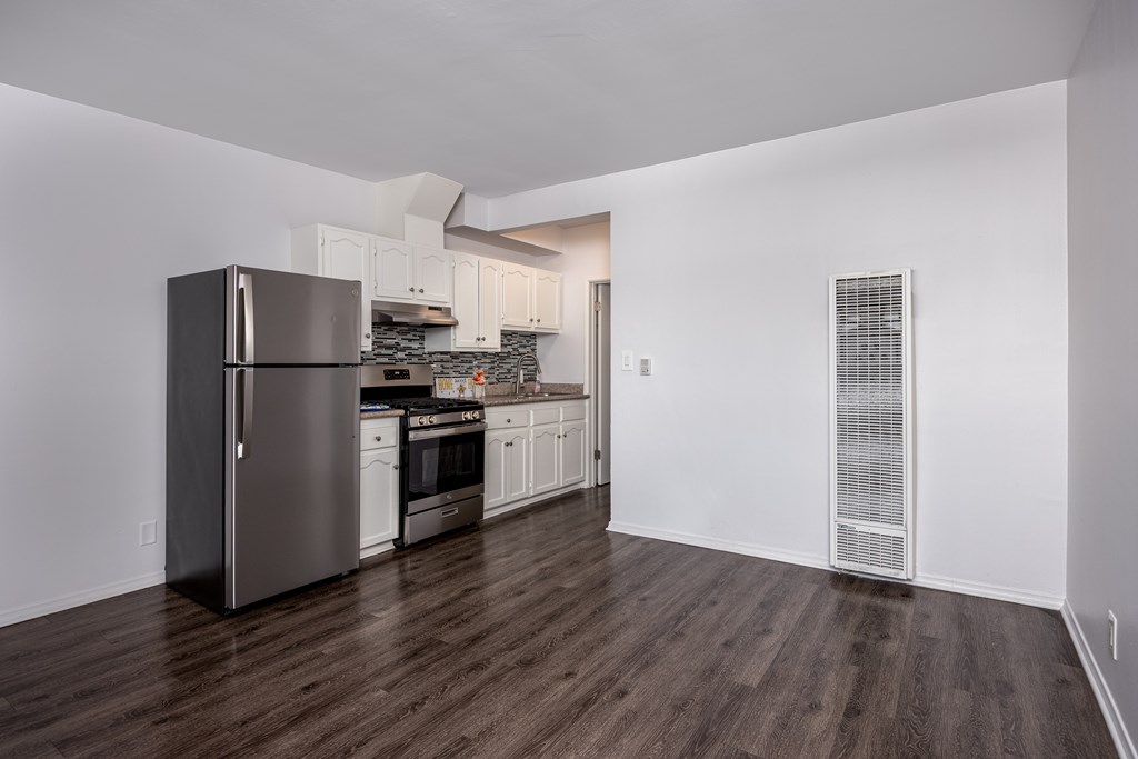 A kitchen with a refrigerator, oven, and cabinets.