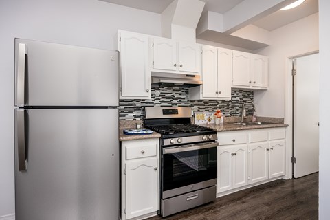 A modern kitchen with a stainless steel refrigerator and white cabinets.