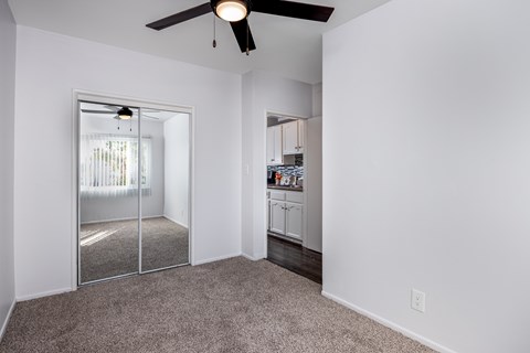 A room with a ceiling fan and a sliding glass door leading to a balcony.