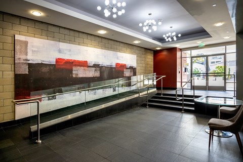 the lobby of a building with a large painting on the wall and a glass counter