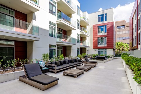 a row of lounge chairs in a courtyard between two apartment buildings