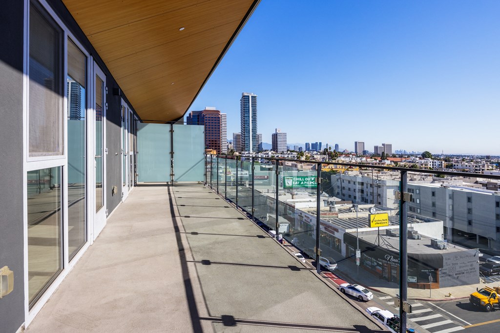 a balcony with glass doors and a city in the background